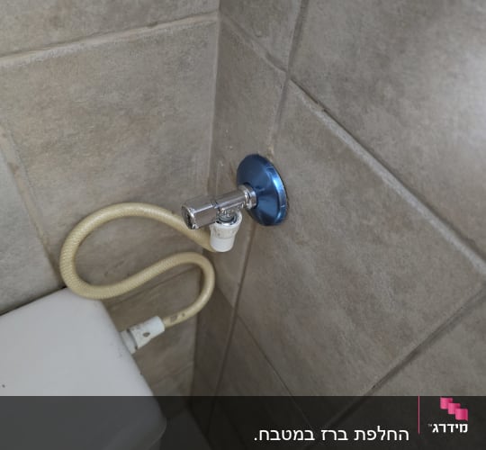 חיבור צינור למיכל שירותים על קיר אריחים